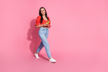 Photo portrait of brunette hair hispanic young smiling lady in bright red stylish blouse using smartphone walking isolated on pink color background