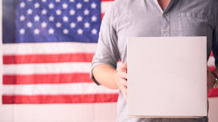 Man Holding Blank Box in Front of American Flag