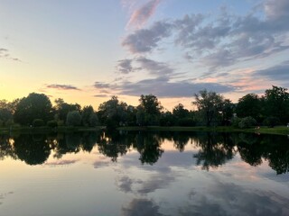 twilights at the park, sky and trees silhouettes reflection on the water surface, pond in the park, evening, summer
