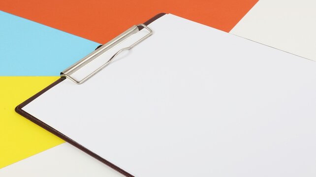 Clipboard document holder with white sheet and colored background copy space.