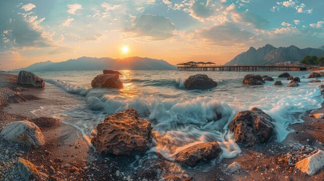 At sunset, quiet waves roll on golden sand of the beach. In the background, beautiful rocks stand out against the golden sand.