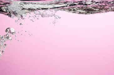 Different waves of air bubbles caused by falling water on a colorful background.