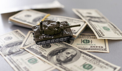 toy tank on the background of dollar bills