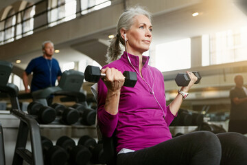 Dumbbell, music and training with mature woman on bench in gym for physical fitness or workout. Exercise, health and weight with confident athlete person in performance club for active challenge