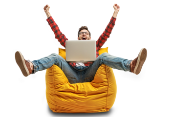 Happy man with raised hands sitting in front of laptop on a yellow bean bag chair. He looks excited and happy, isolated on white or transparent png.