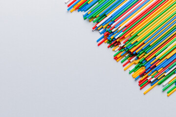 Heap of colorful plastic drinking straws on Colored background, flat lay. Copy Space for text