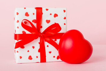 gift box with red bow and red heart on colored background. Perspective view. Flat lay