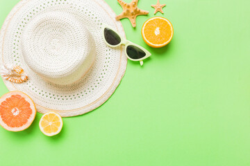 Top view of various seashells placed near colorful fruit and stylish summer accessories on table...