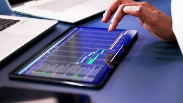 African American woman using Gantt software to manage project schedule and control finances on computer