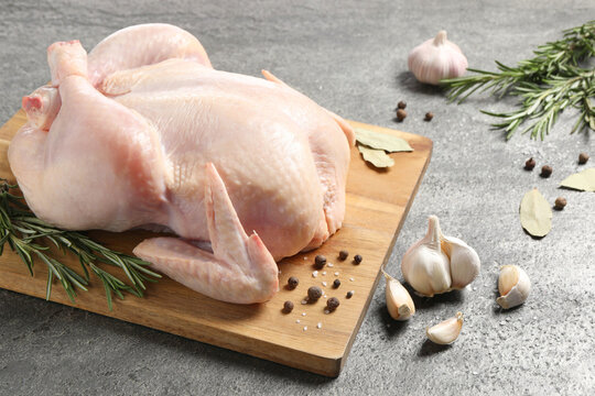 Fresh raw chicken with spices on grey textured table