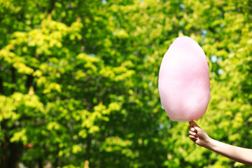 Woman holding sweet cotton candy outdoors, closeup. Space for text