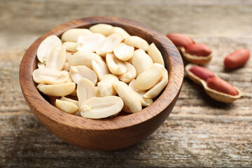 Fresh peanuts in bowl on wooden table, closeup