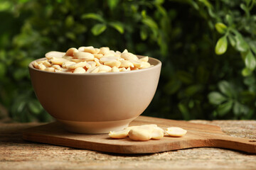 Fresh peanuts in bowl on wooden table against blurred background, space for text