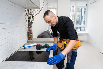 Man electrical repairs kitchen surface apartment. Installing hob in countertop. Man bought new...
