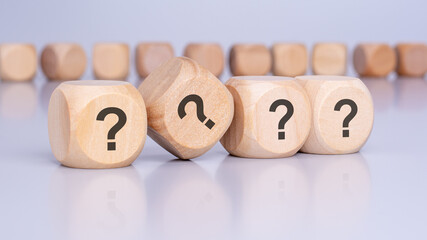 four wooden blocks with question marks over a brown background with copy space
