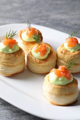 Delicious puff pastry with avocado cream, salmon and dill on grey table