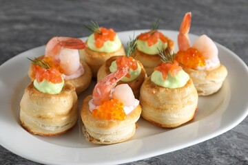 Different delicious puff pastry snacks on grey table