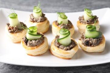 Delicious puff pastry with mushrooms, cucumber and dill on grey table, closeup
