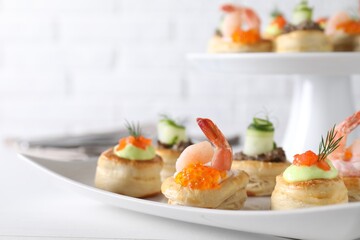 Different delicious puff pastry snacks on white table