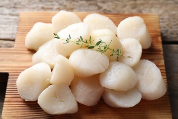 Fresh raw scallops and thyme on wooden table, closeup