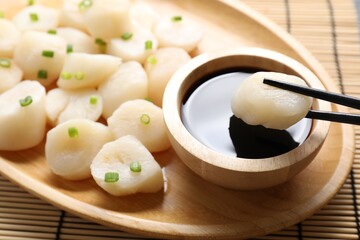 Taking raw scallop with chopsticks at bamboo mat, closeup