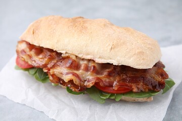 Tasty sandwich with bacon on grey table, closeup