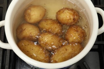Boiling young potatoes in pot on stove