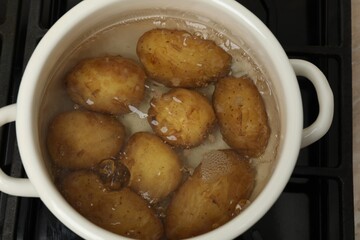 Boiling young potatoes in pot on stove, top view
