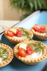 Delicious canapes with dry smoked sausages, cream cheese and vegetables on table, closeup