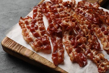 Slices of tasty fried bacon on black table