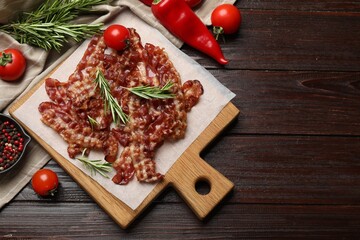 Slices of tasty fried bacon, tomatoes and different spices on wooden table, top view. Space for text