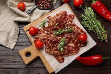 Slices of tasty fried bacon, tomatoes and different spices on wooden table, top view