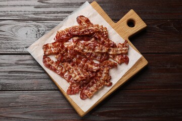 Slices of tasty fried bacon on wooden table, top view