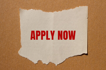 Apply now message written on ripped paper with cardboard background. Conceptual apply now symbol. Copy space.