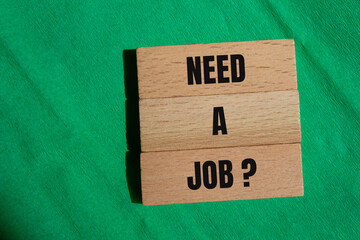 Need a job words written on wooden blocks with green background. Conceptual need a job question symbol. Copy space.