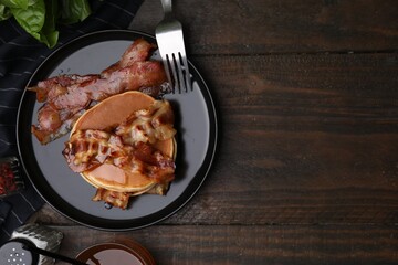 Delicious pancakes with fried bacon served on wooden table, flat lay. Space for text