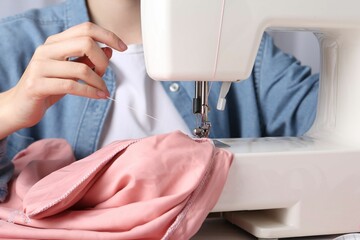 Seamstress working with sewing machine at table indoors, closeup