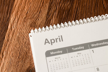 White calendar of the month of April on a wooden background. Planning, goal setting, agenda, planner, organization and time management concept.