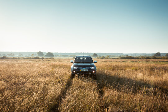 black Mitsubishi SUV pickup truck in a meadow. Morning light at 6am, symmetric view from the front. Chernihiv region, Ukraine - August  01 2015.