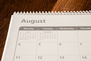 White calendar of the month of August on a wooden background. Planning, goal setting, agenda, planner, organization and time management concept.