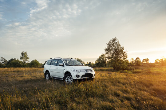 white Mitsubishi Pajero Sport SUV in a meadow. Sunset, three quarter view. Chernihiv region, Ukraine - July 30 2015.