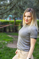 Fototapeta premium Young smiling blonde woman wearing a grey t-shirt in the park
