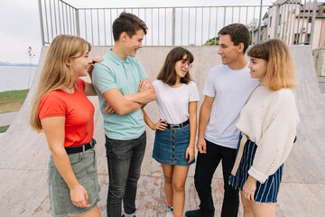 Summer holidays and teenage concept - group of smiling teenagers hanging out outside.