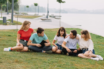 Fototapeta premium Summer holidays and teenage concept - group of smiling teenagers with tablet hanging out outside.