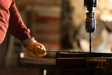 Worker drills iron with a bench drill. Metal Drill bit drills hole in steel billet on industrial machine. Metal processing industry. A metal workshop in Turkey