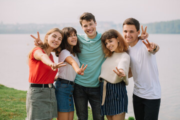 Summer holidays and teenage concept - group of smiling teenagers hanging out outside.