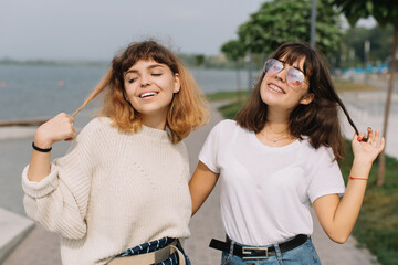 Two stylish teens schoolgirls joking and smiling togather on the street at school