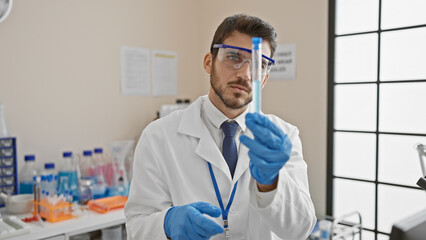 Hispanic scientist man examining a test tube in a laboratory setting, portraying medical research and healthcare professionalism.