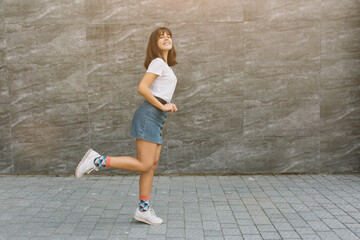 Pretty teen girl with braces in glasses posing near gray wall