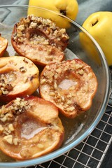 Tasty baked quinces with walnuts and honey in bowl on table, closeup